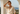 Woman in a white outfit standing on a balcony with a scenic view.
